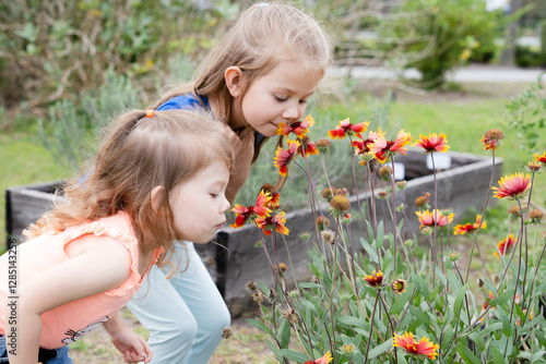 Cute Caucasian little kids smell the flowers in the butterfly garden. Children and nature concept. Kids and gardening. Kids' summer activities and fun concept