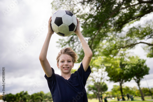 Little adorable toddler boy playing with ball outdoors. Happy smiling child catching and throwing ball, looking camera, making sports. Active leisure with children and kids.