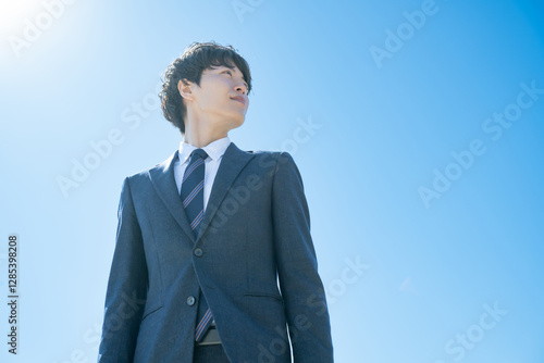 Fotografía 空に向かって立つスーツを着た男性
