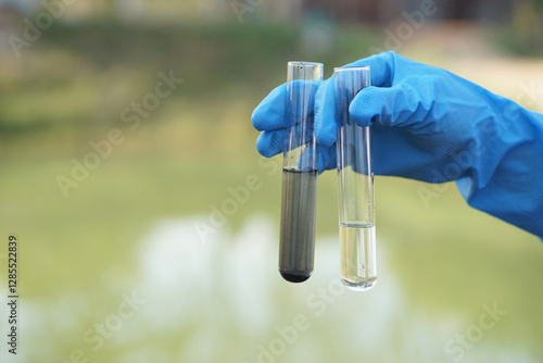 Close up scientist hand hold glass tube that contains sample of water to do science experiment. Concept Testing of water quality and contaminants from natural water sources        