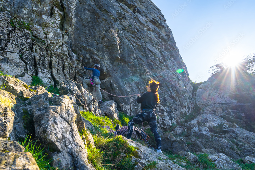 Women climbers ascending rock face in bright sunlight