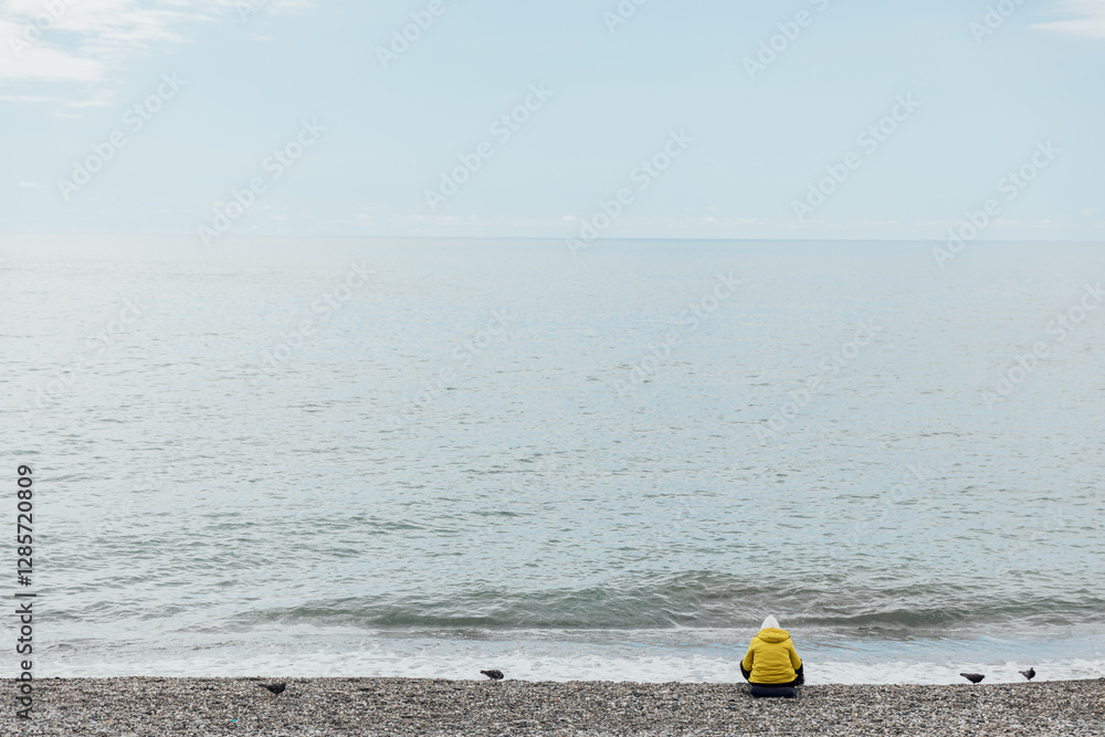 One person sitting on the beach and looking at the sea One person sitting on the beach and looking at the sea