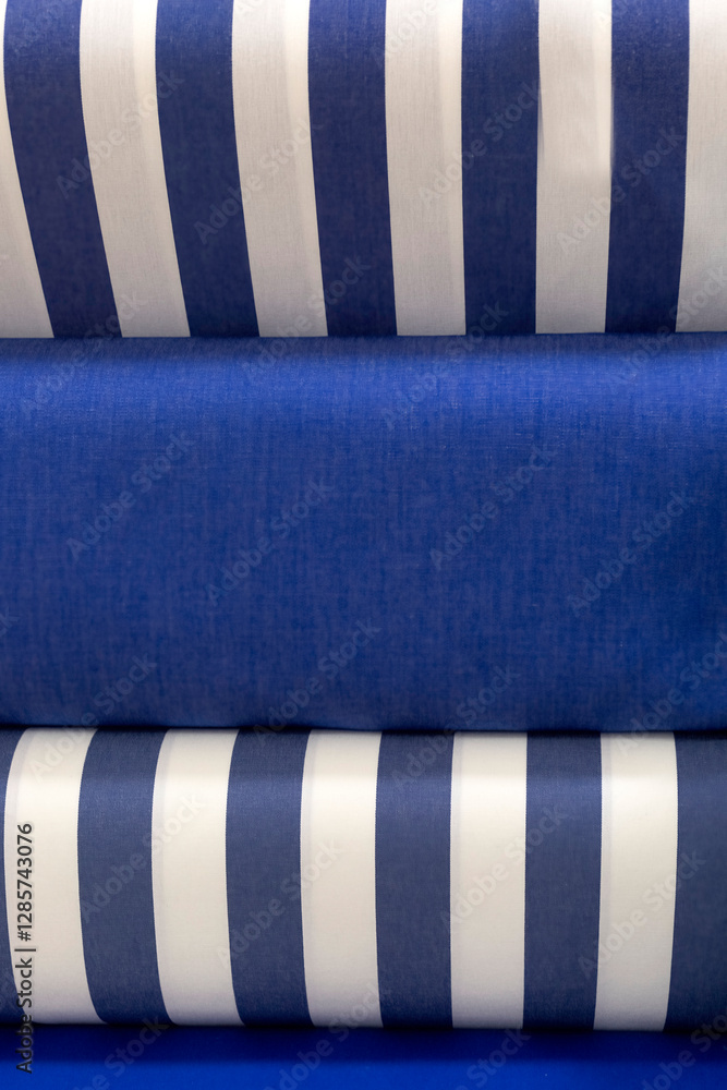 Fototapeta premium Colourful bolts of blue and white fabric cloth on a market stall for use as a background texture
