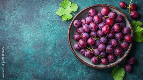 Obraz na płótnie A bowl of red grapes with green leaves on a blue background w salonie