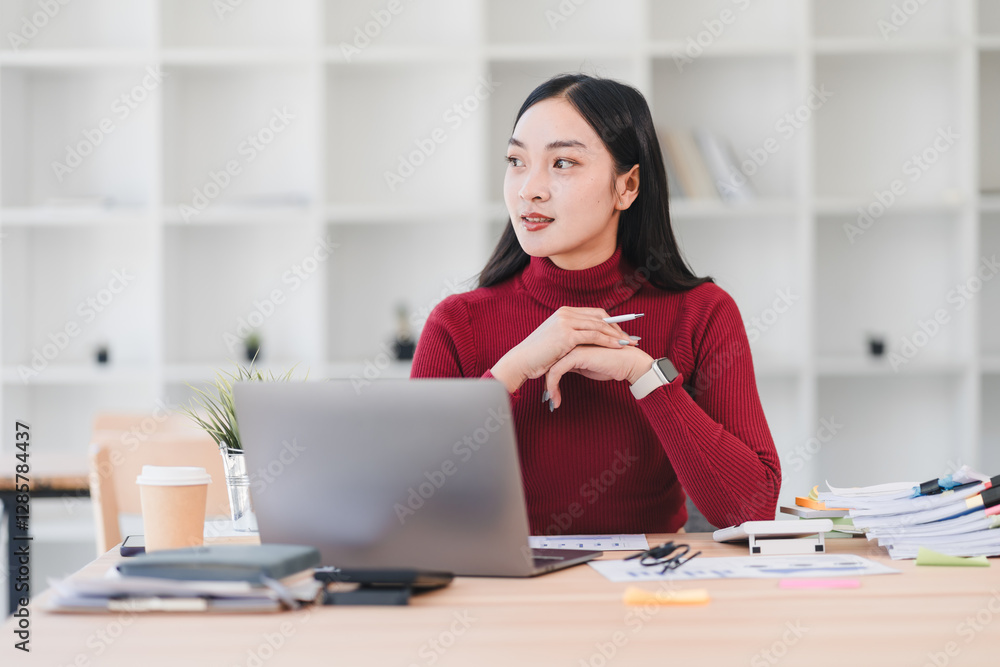 Woman in red sweater sits at desk with laptop, papers, and office supplies, appearing thoughtful in modern office setting. Woman in red sweater sits at desk with laptop, papers, and office supplies, appearing thoughtful in modern office setting.