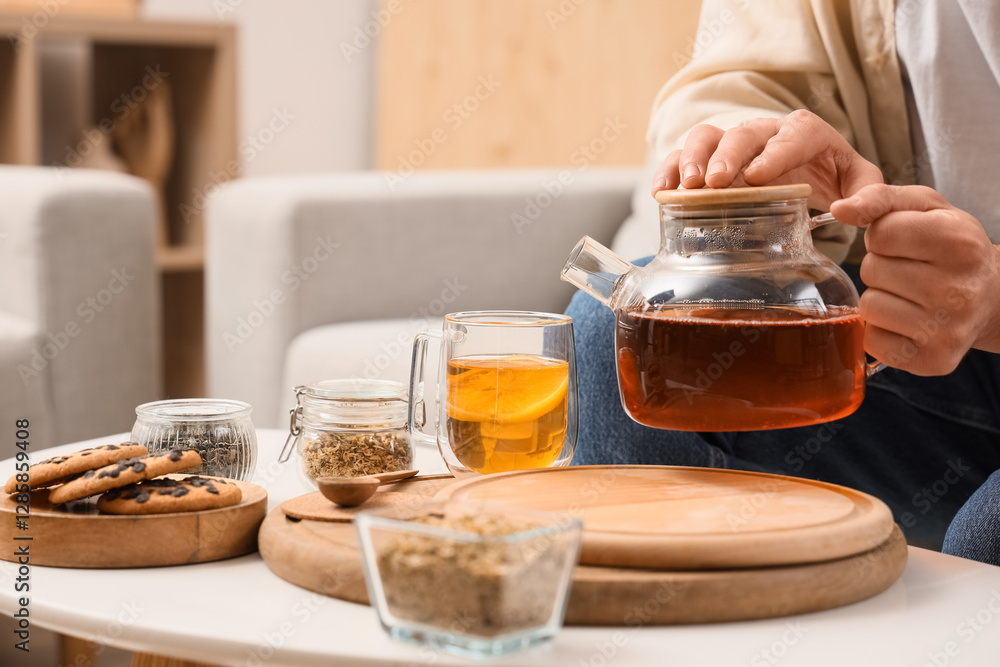 Young man pouring lemon tea into cup at home, closeup Young man pouring lemon tea into cup at home, closeup