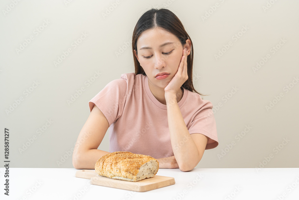Gluten allergy asian young woman expression face, looking bread refusing to eat on plate in breakfast food meal, girl having a stomach ache. Gluten intolerant and Gluten free, diet getting fat concept Gluten allergy asian young woman expression face, looking bread refusing to eat on plate in breakfast food meal, girl having a stomach ache. Gluten intolerant and Gluten free, diet getting fat concept
