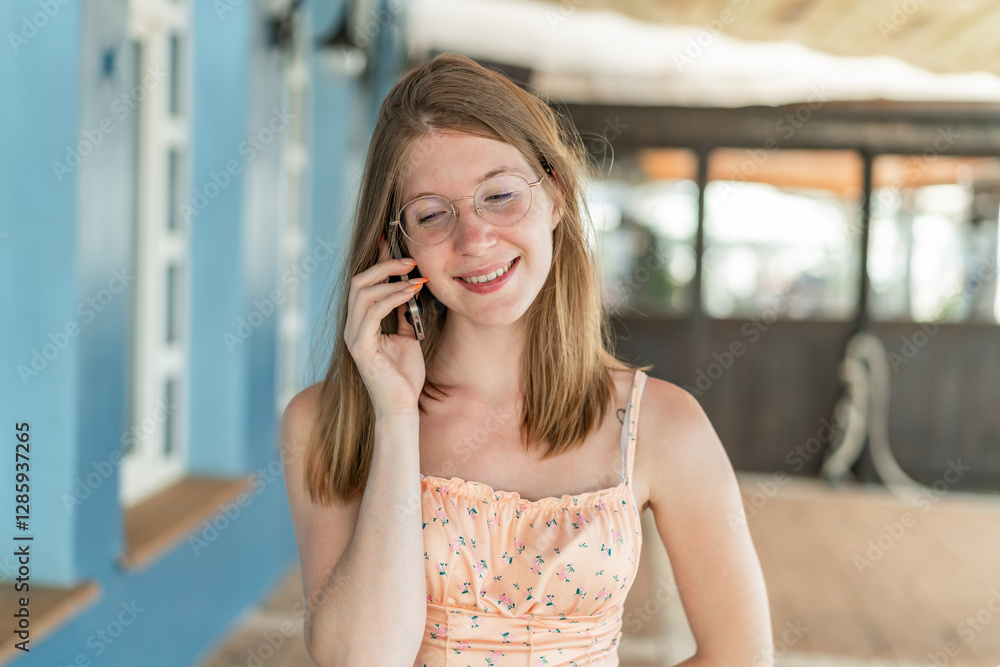 Fototapeta premium Young French girl with glasses at outdoors keeping a conversation with the mobile phone with someone