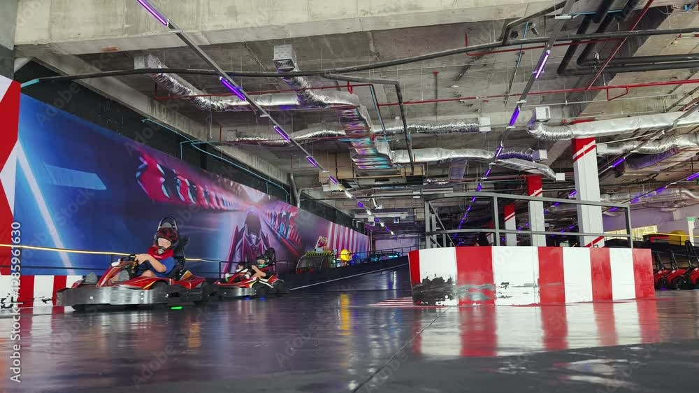 A group races gokarts at indoor track enjoying engine sounds and sharp turns