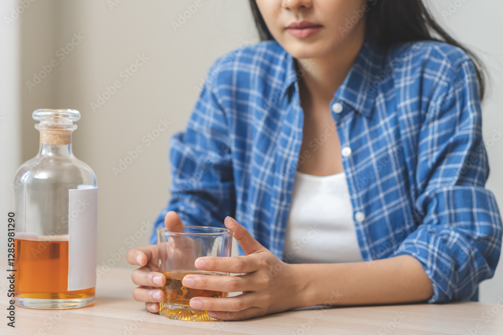 Alcoholism drunk asian young woman hand holding glass of alcohol or whiskey, female sitting alone, drinking on table at home, at night. Treatment of alcohol addiction, suffer abuse problem alcoholism Alcoholism drunk asian young woman hand holding glass of alcohol or whiskey, female sitting alone, drinking on table at home, at night. Treatment of alcohol addiction, suffer abuse problem alcoholism
