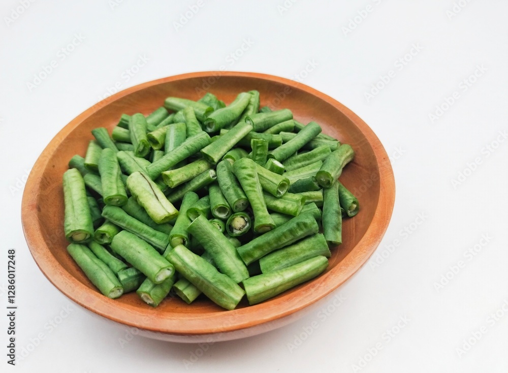 Long beans (Vigna Unguiculata ssp. Sesquipedalis) that have been cut into pieces in a wooden bowl on a white background. High angle view. Long beans (Vigna Unguiculata ssp. Sesquipedalis) that have been cut into pieces in a wooden bowl on a white background. High angle view.