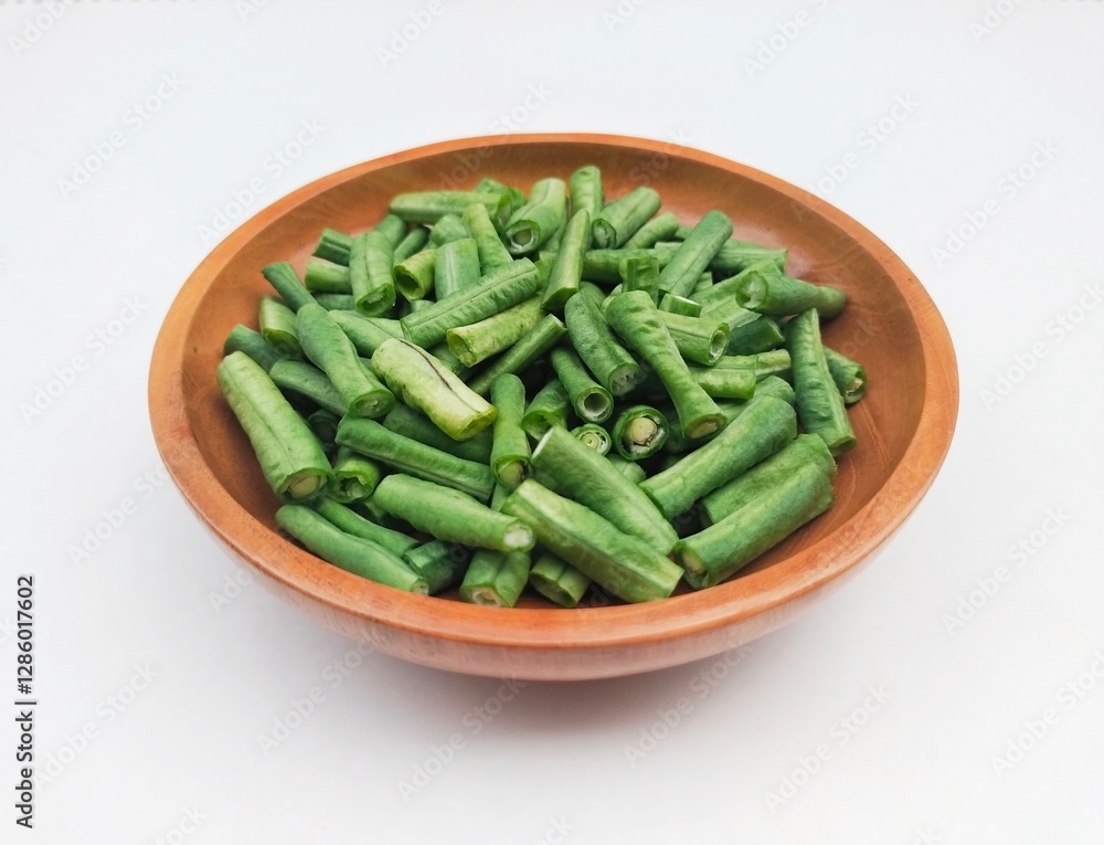 Long beans (Vigna Unguiculata ssp. Sesquipedalis) that have been cut into pieces in a wooden bowl on a white background. High angle view. Long beans (Vigna Unguiculata ssp. Sesquipedalis) that have been cut into pieces in a wooden bowl on a white background. High angle view.