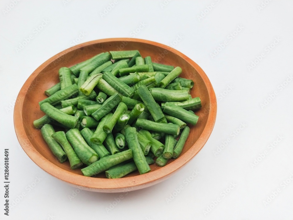 Long beans (Vigna Unguiculata ssp. Sesquipedalis) that have been cut into pieces in a wooden plate on a white background. Long beans (Vigna Unguiculata ssp. Sesquipedalis) that have been cut into pieces in a wooden plate on a white background.