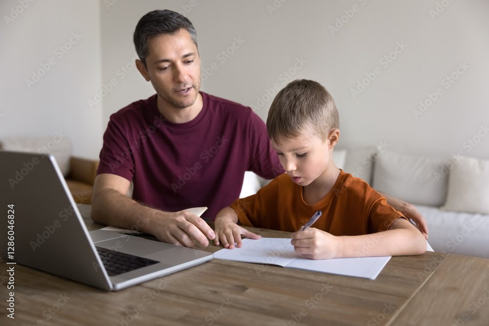 Caring father helps with task to his little school age son. Little boy writing exercise in copybook, make notes, listen explanation of man teacher or tutor sit together at table with laptop. Education Caring father helps with task to his little school age son. Little boy writing exercise in copybook, make notes, listen explanation of man teacher or tutor sit together at table with laptop. Education