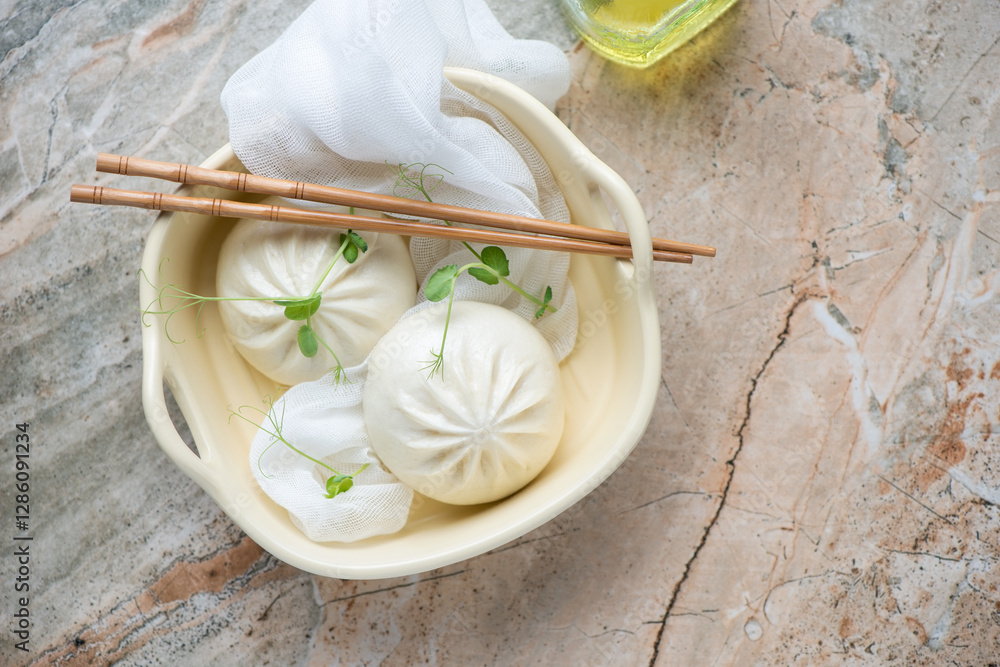 Fotografie Serving tray with steamed baozi buns on a grey and roseate granite background, h