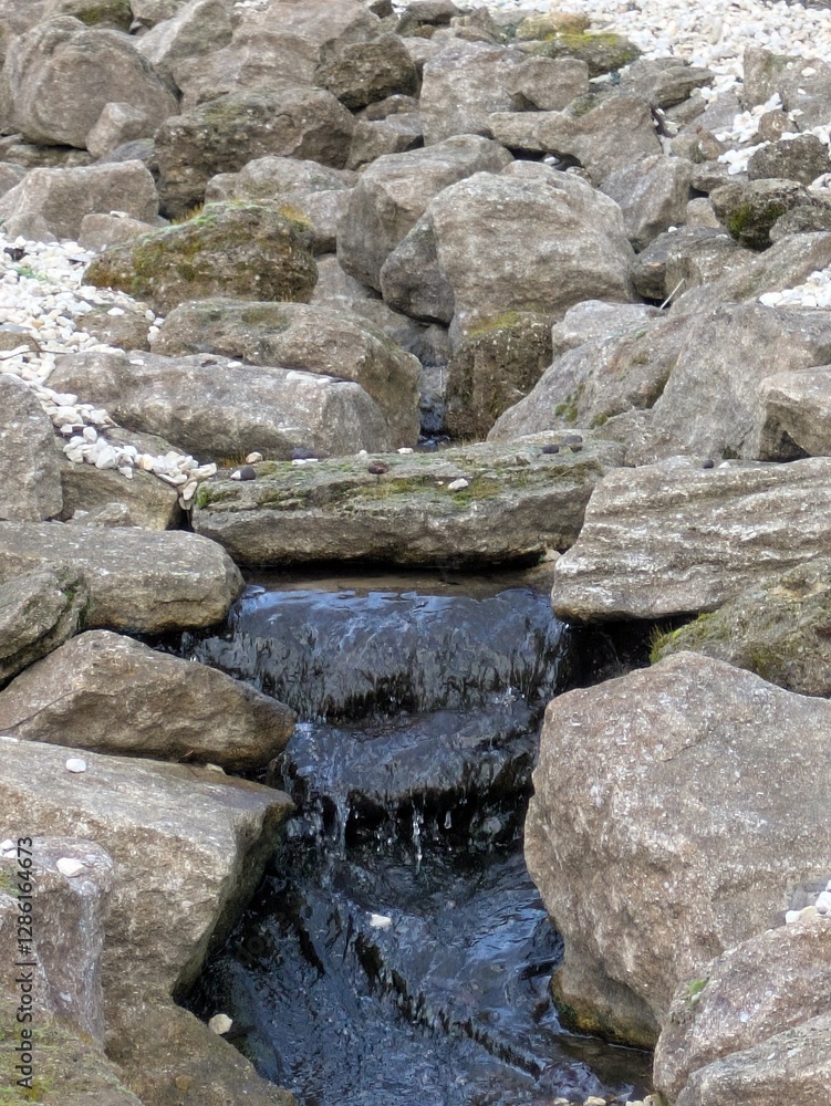 A gentle stone stream with rocks and flowing water A gentle stone stream with rocks and flowing water