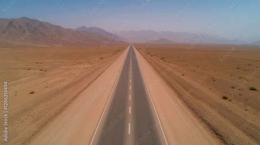 Fototapeta premium deserted highway stretches through vast desert landscape, surrounded by mountains and arid terrain, evoking sense of solitude and adventure
