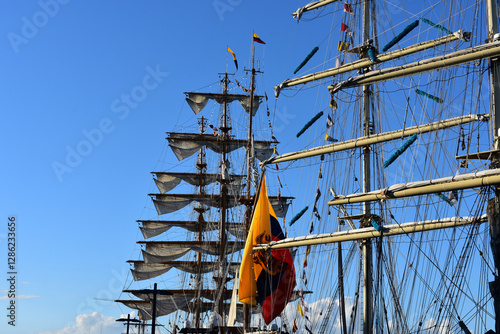 Tall sailing ships with intricate rigging and unfurled sails set against a clear blue sky. Colorful flags and maritime details. photo