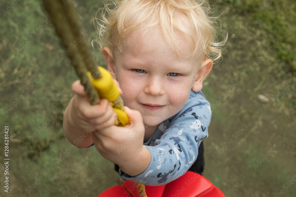 Small Blonde Boy with Blue Eyes holding a Rope with plate, Looking Up Happily (Top View) Small Blonde Boy with Blue Eyes holding a Rope with plate, Looking Up Happily (Top View)