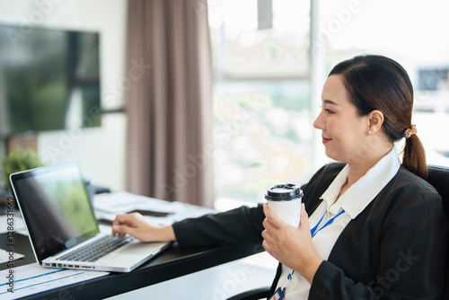 Busy mature middle aged professional business woman executive, female bank manager or entrepreneur looking at laptop computer in corporate office working sitting at desk. Authentic candid shot..
