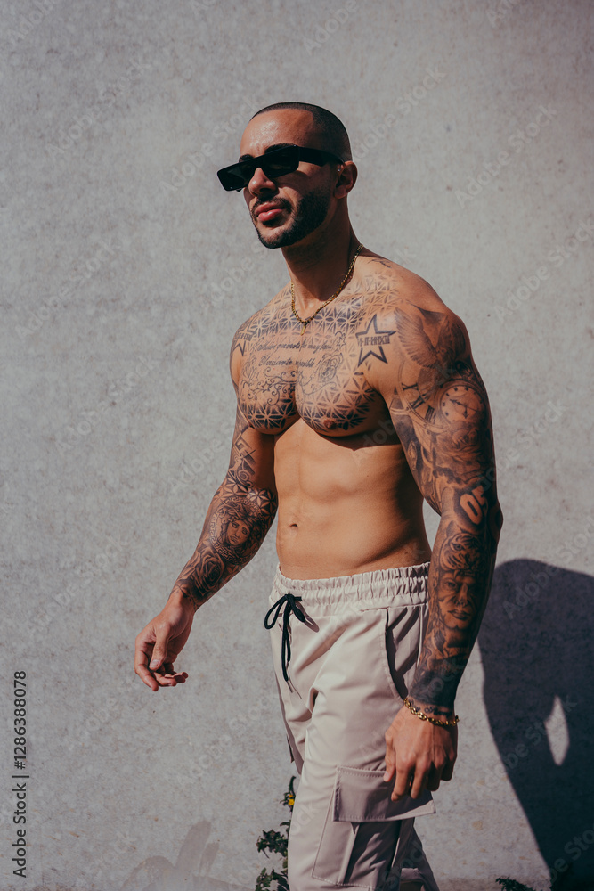 Chico joven tatuado posando con ropa actual en la calle