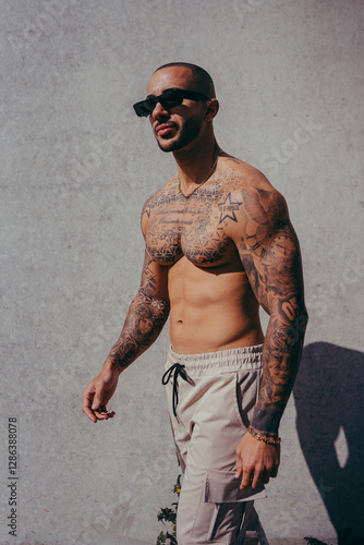Obraz na płótnie Chico joven tatuado posando con ropa actual en la calle w salonie