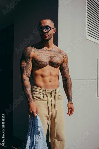 Obraz na płótnie Chico joven tatuado posando con ropa actual en la calle w salonie
