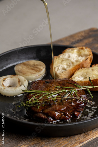 Pan-fried steak with toast and rosemary, drizzled with olive oil