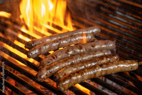 Grilling sausages on the grill with flames and smoke.