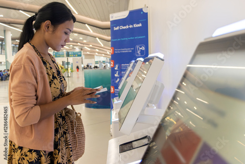 Papier peint Young woman using self check-in kiosks in airport terminal.