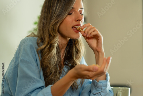 Obraz na plátně Young woman eating walnuts, mindful healthy snack while working from home