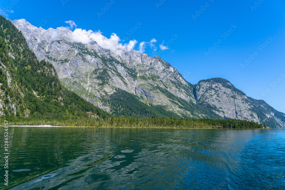 Beautiful panorama view of Konigssee Lake with peak Watzmann and Bavarian alps in background in Berchtesgaden national park on a sunny summer day with blue sky and cloud, Schoenau, Bavaria, Germany Beautiful panorama view of Konigssee Lake with peak Watzmann and Bavarian alps in background in Berchtesgaden national park on a sunny summer day with blue sky and cloud, Schoenau, Bavaria, Germany