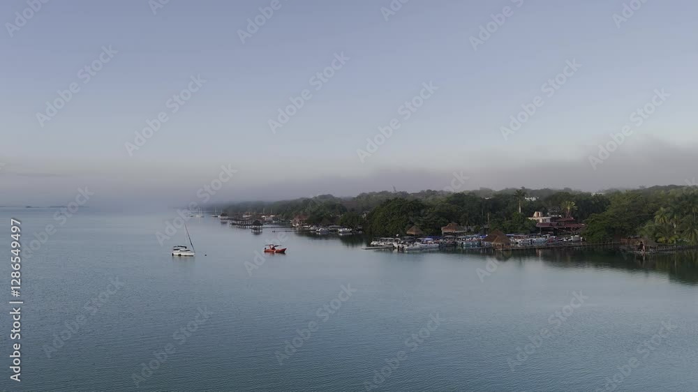 drone shot over the Baccalar lagoon, a tropical setting of houses on the waterside with boats moored to docks. drone shot over the Baccalar lagoon, a tropical setting of houses on the waterside with boats moored to docks.