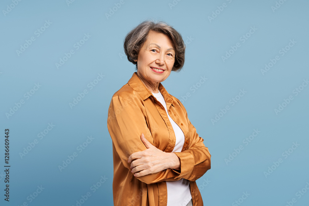 Smiling senior woman with crossed arms on blue background Smiling senior woman with crossed arms on blue background