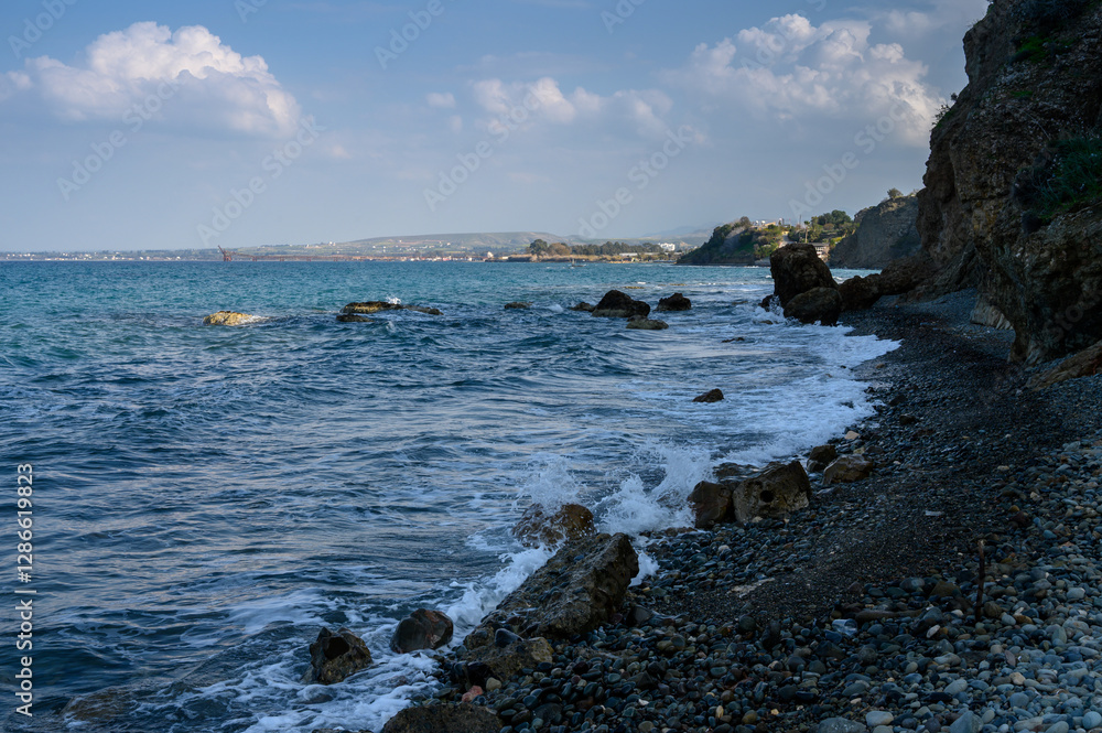 Waves crash against a rugged shoreline under a cloudy sky in a tranquil coastal setting Waves crash against a rugged shoreline under a cloudy sky in a tranquil coastal setting