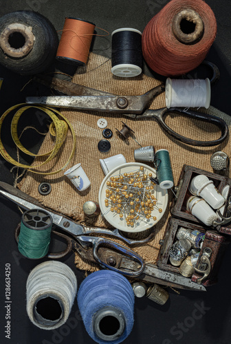 Obraz na płótnie Steel scissors, Spools of thread of various colors, Thimbles in small wooden treasure chest, Sewing needles stuck in a green miniature spools thread and Measuring tape including pins in small tray. w salonie