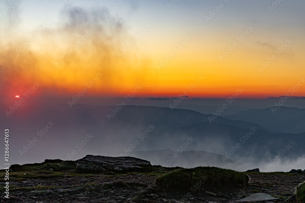 Fototapeta premium orange sky after sunset, view from the top of Mount Petros, clouds swirling around