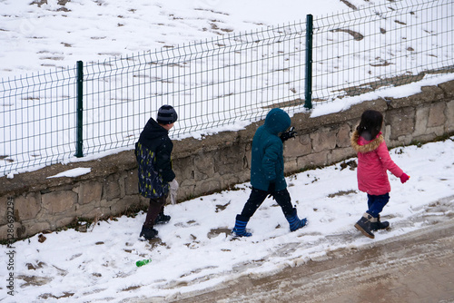 Obraz na płótnie It snowed and the little friend kids are walking on the snow, w salonie