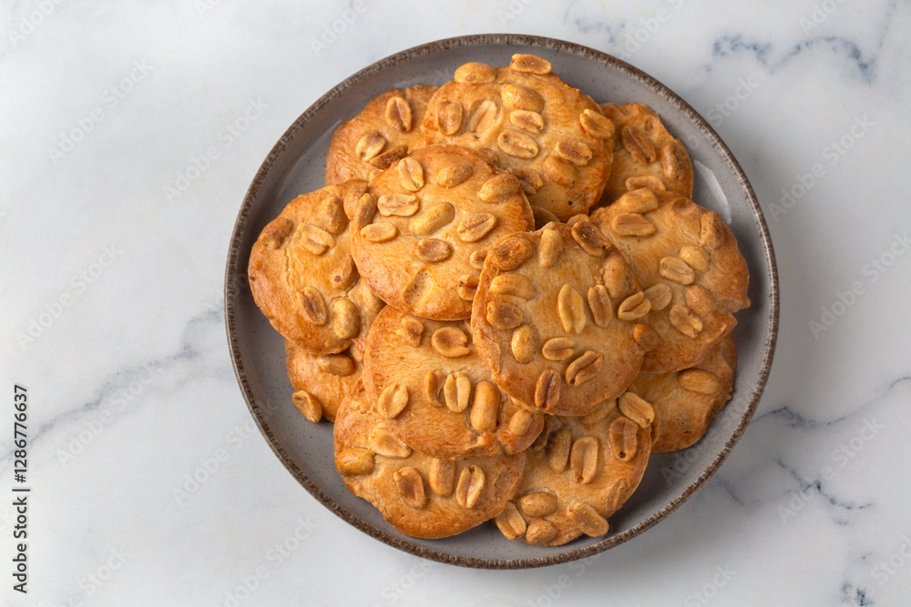 Tasty peanut cookies and butter on beige background
