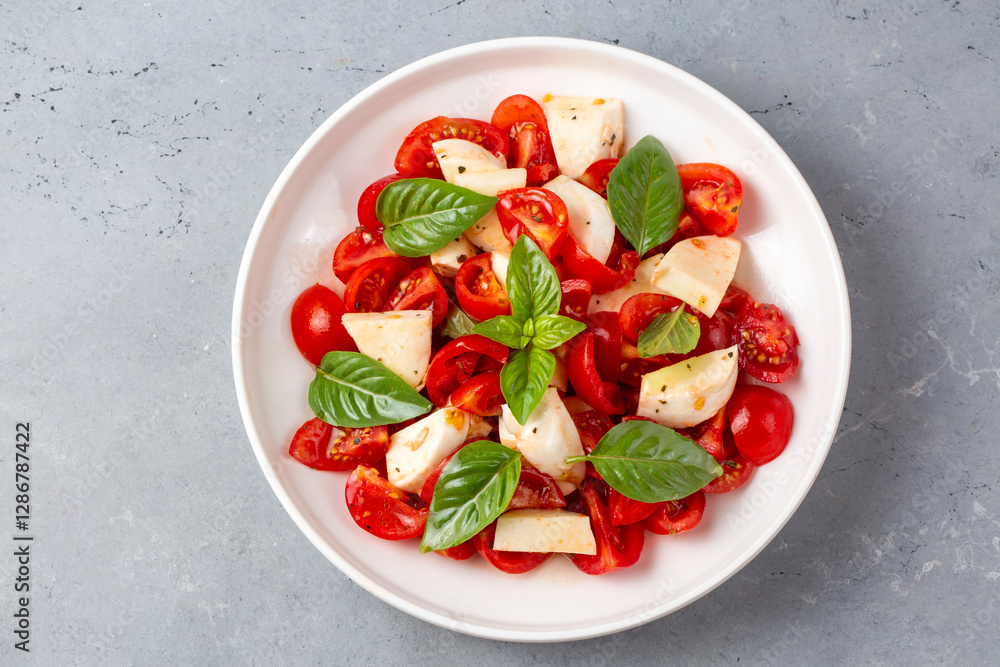 Italian caprese salad with sliced tomatoes, mozzarella, basil, olive oil