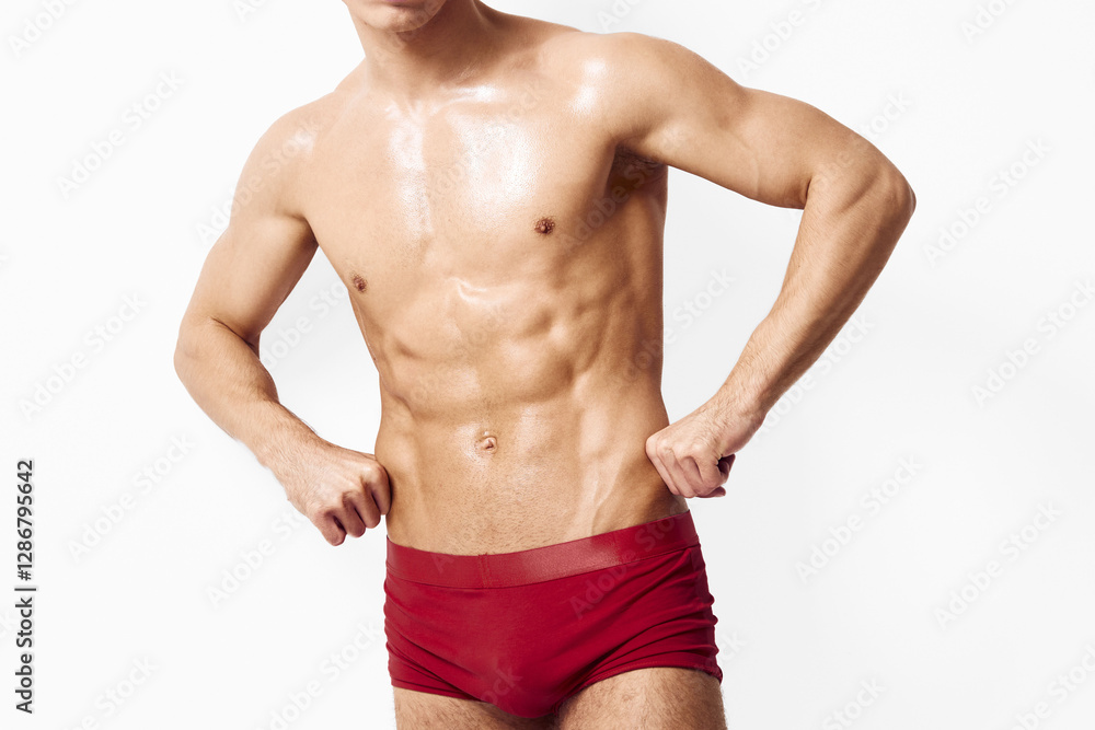 Confident young man with toned physique posing in red swimwear, showcasing athleticism and strength. Fitness and lifestyle concept with a clean, minimalist background. Confident young man with toned physique posing in red swimwear, showcasing athleticism and strength. Fitness and lifestyle concept with a clean, minimalist background.