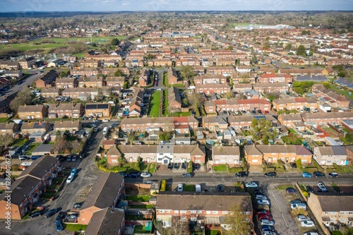 An aerial photo shows a dense suburban neighborhood of closely-packed, brick single-family homes with pitched roofs and small, well-kept yards.