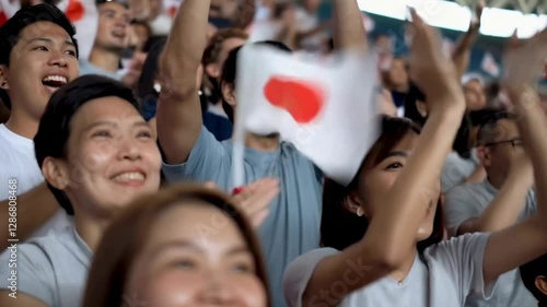 Fans celebrating and waving Japan flag at a sports event
