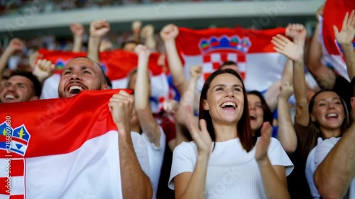 Fans celebrating and waving Croatia flags at a sports event
