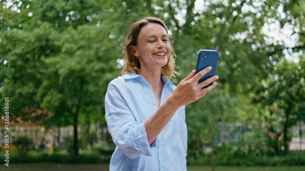 Woman enjoy video phone conversation walking urban park closeup. Lady greeting Woman enjoy video phone conversation walking urban park closeup. Lady greeting
