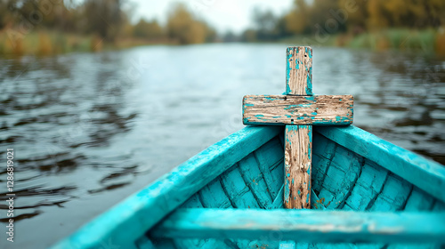 Weathered cross on teal boat, autumn river.  Spiritual journey, faith concept