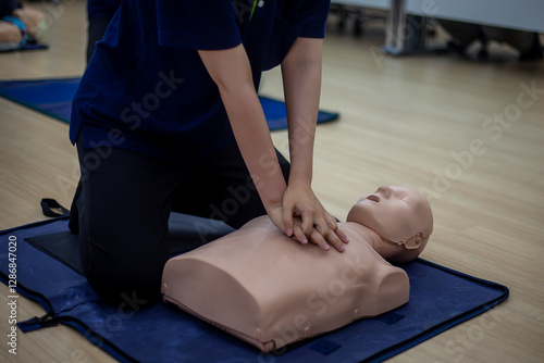 Close-up of Asian hands practicing cardiopulmonary resuscitation (CPR) on a training dummy. Important techniques include chest compressions and maintaining an airway.