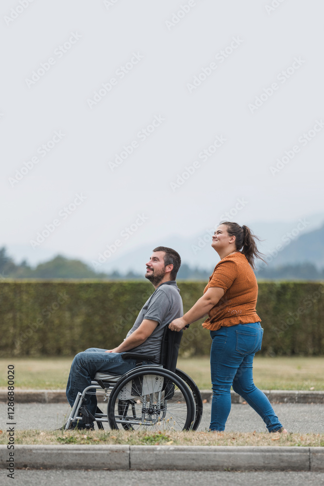 Happy and smiling man with physical disability and his female assistant having a great time together while walking outdoors. Happy and smiling man with physical disability and his female assistant having a great time together while walking outdoors.