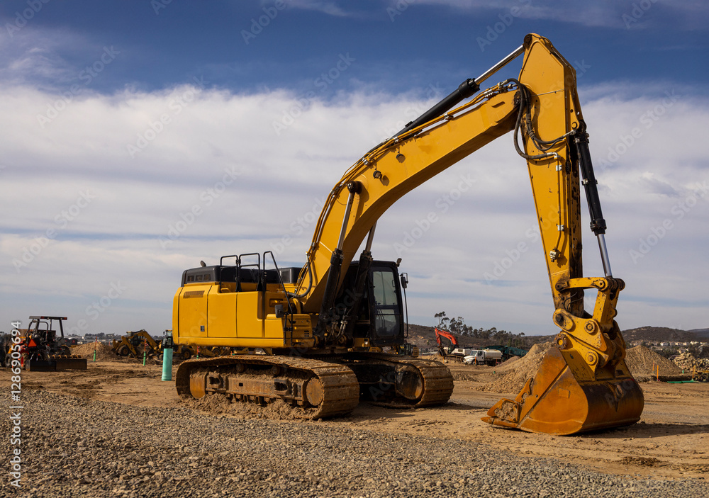 An excavator with digging bucket agaisnt a blue sky with clouds. The angle is from the front of the machine An excavator with digging bucket agaisnt a blue sky with clouds. The angle is from the front of the machine