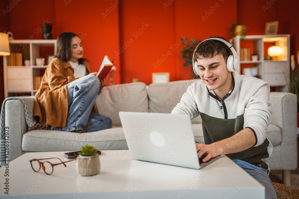man work from home on laptop while woman read a book on sofa man work from home on laptop while woman read a book on sofa